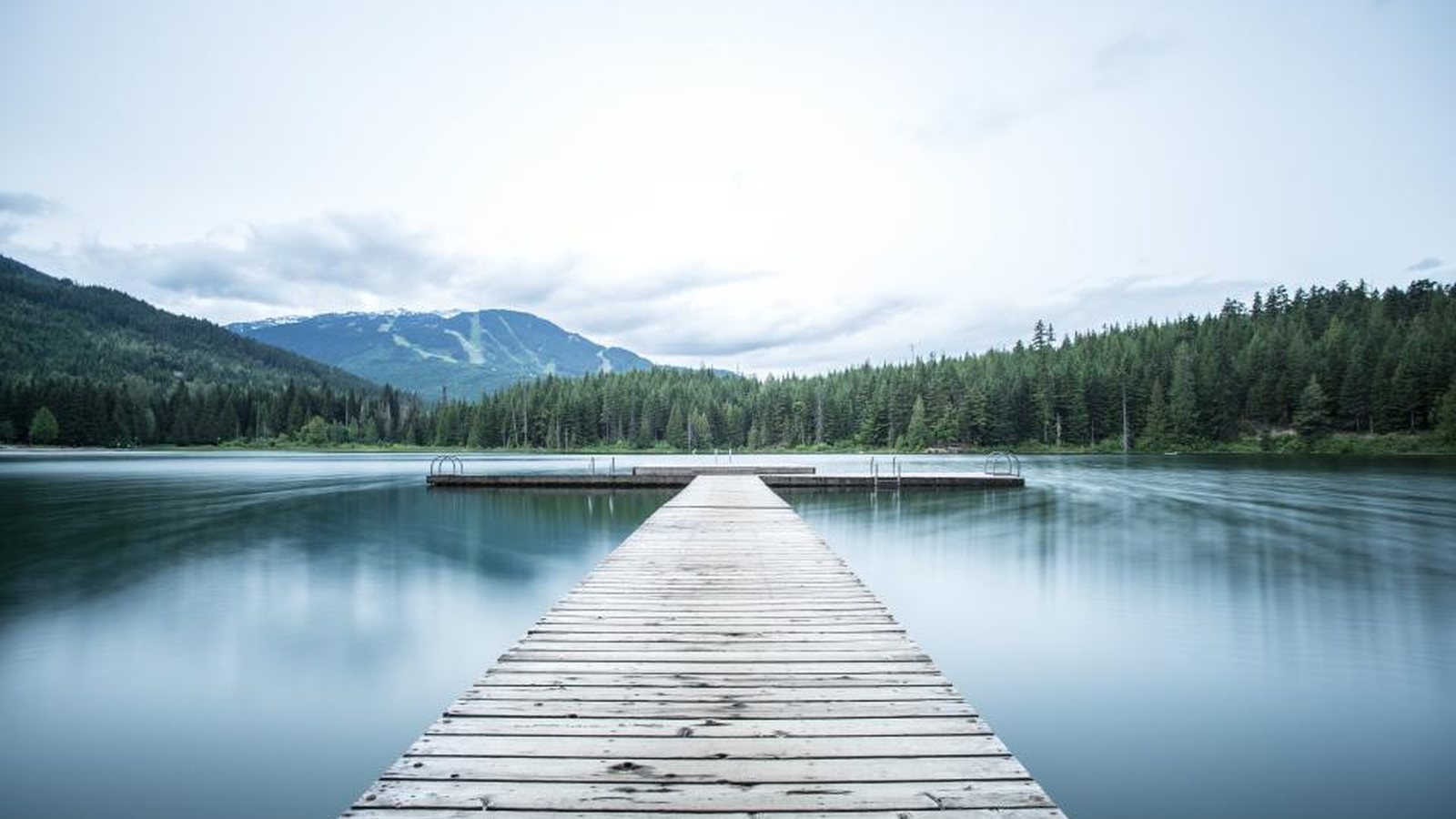 Wooden dock on a forested lake, like the waterways the Riverstone community is built around
